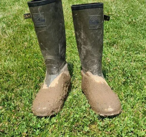 A pair of brown rubber boots in the grass.
