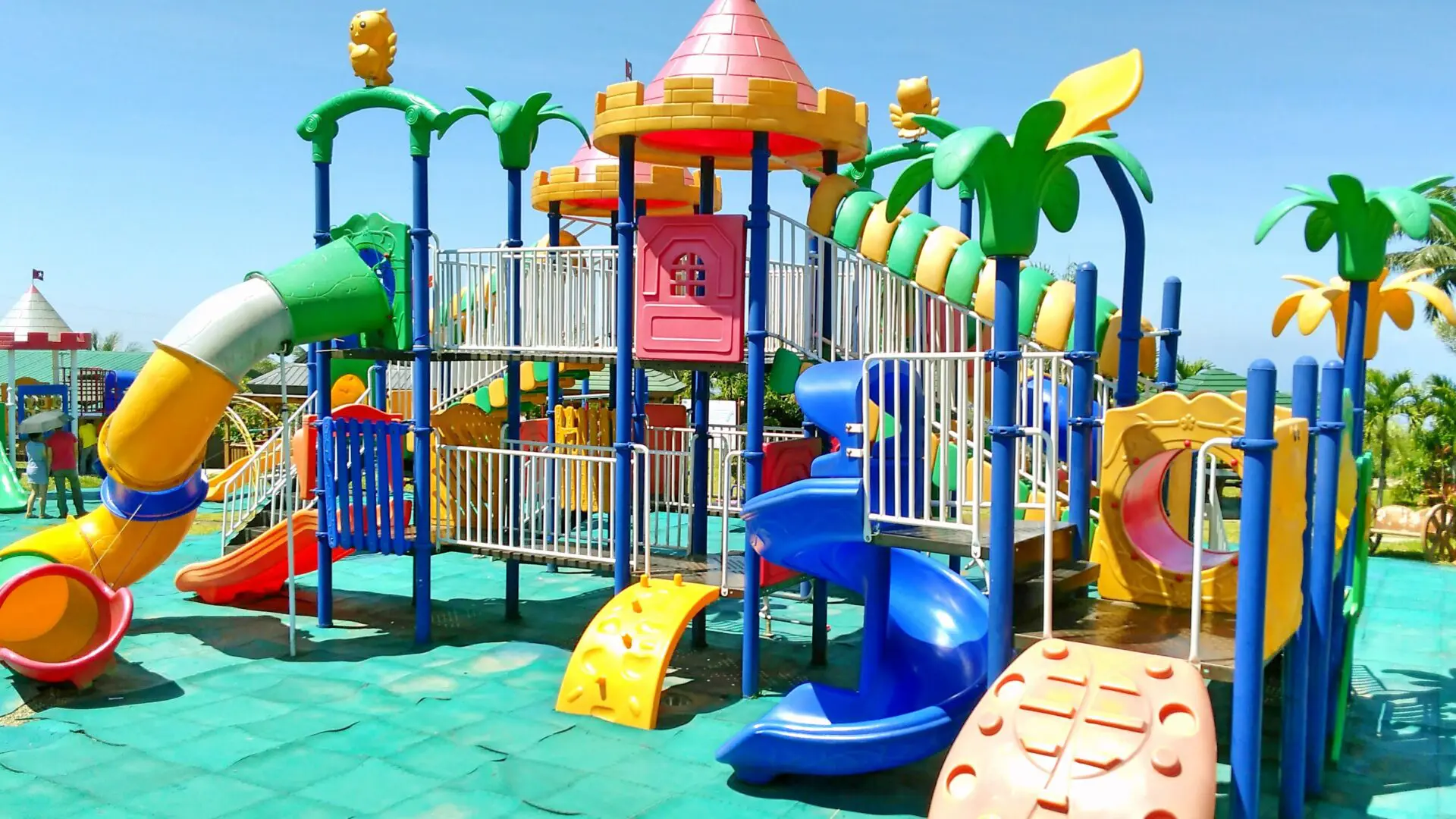 Colorful outdoor playground with slides and climbing structures under a clear sky.