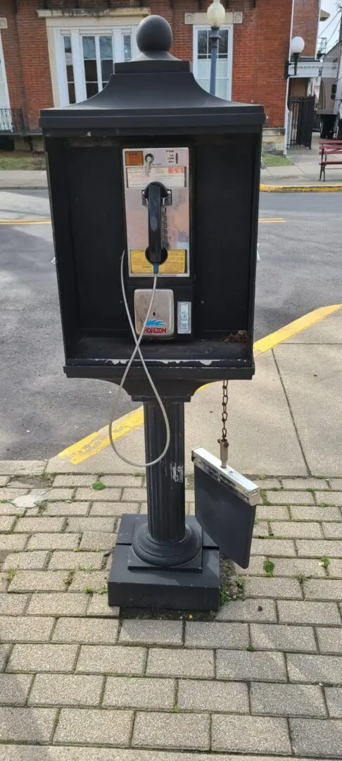 Vintage black outdoor payphone on sidewalk