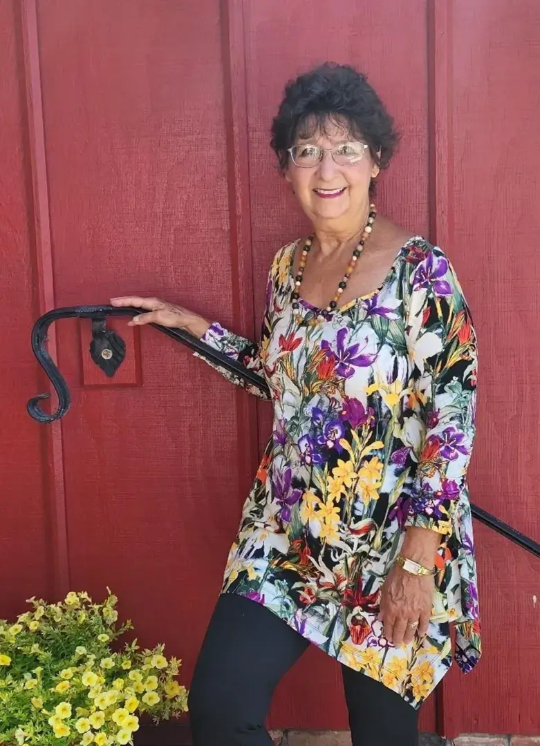 Smiling woman in floral dress by railing.