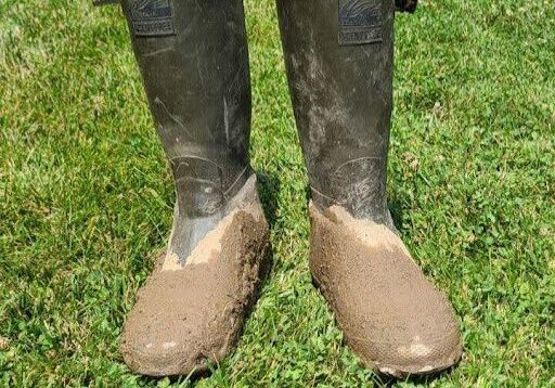A pair of brown rubber boots in the grass.